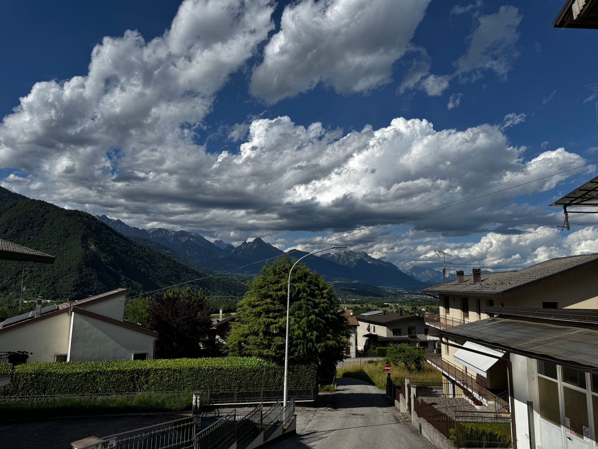 View of houses in Seren del Grappa with the Dolomite mountains and a dramatic cloudy sky in the background.