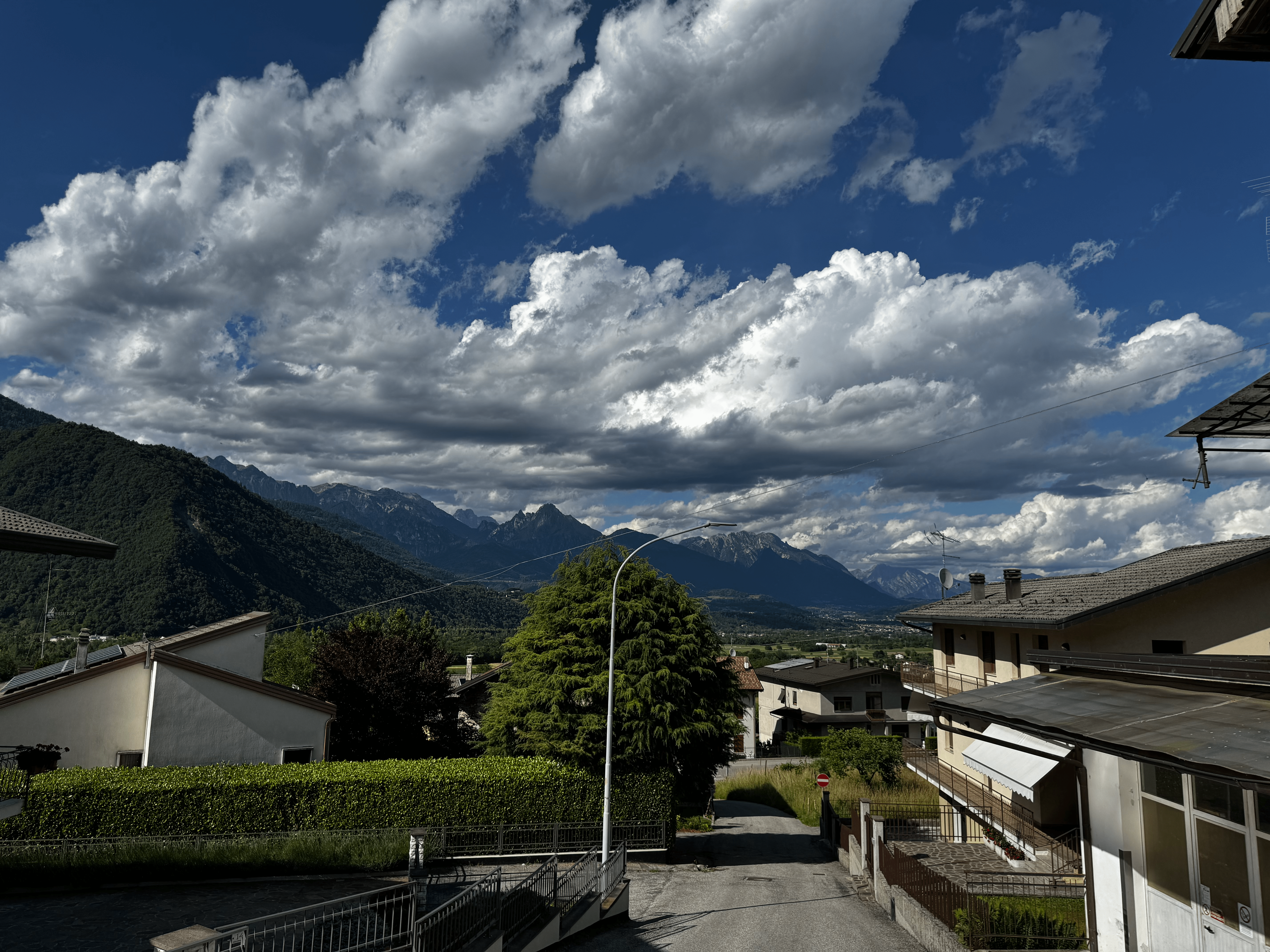 View of houses in Seren del Grappa with the Dolomite mountains and a dramatic cloudy sky in the background.