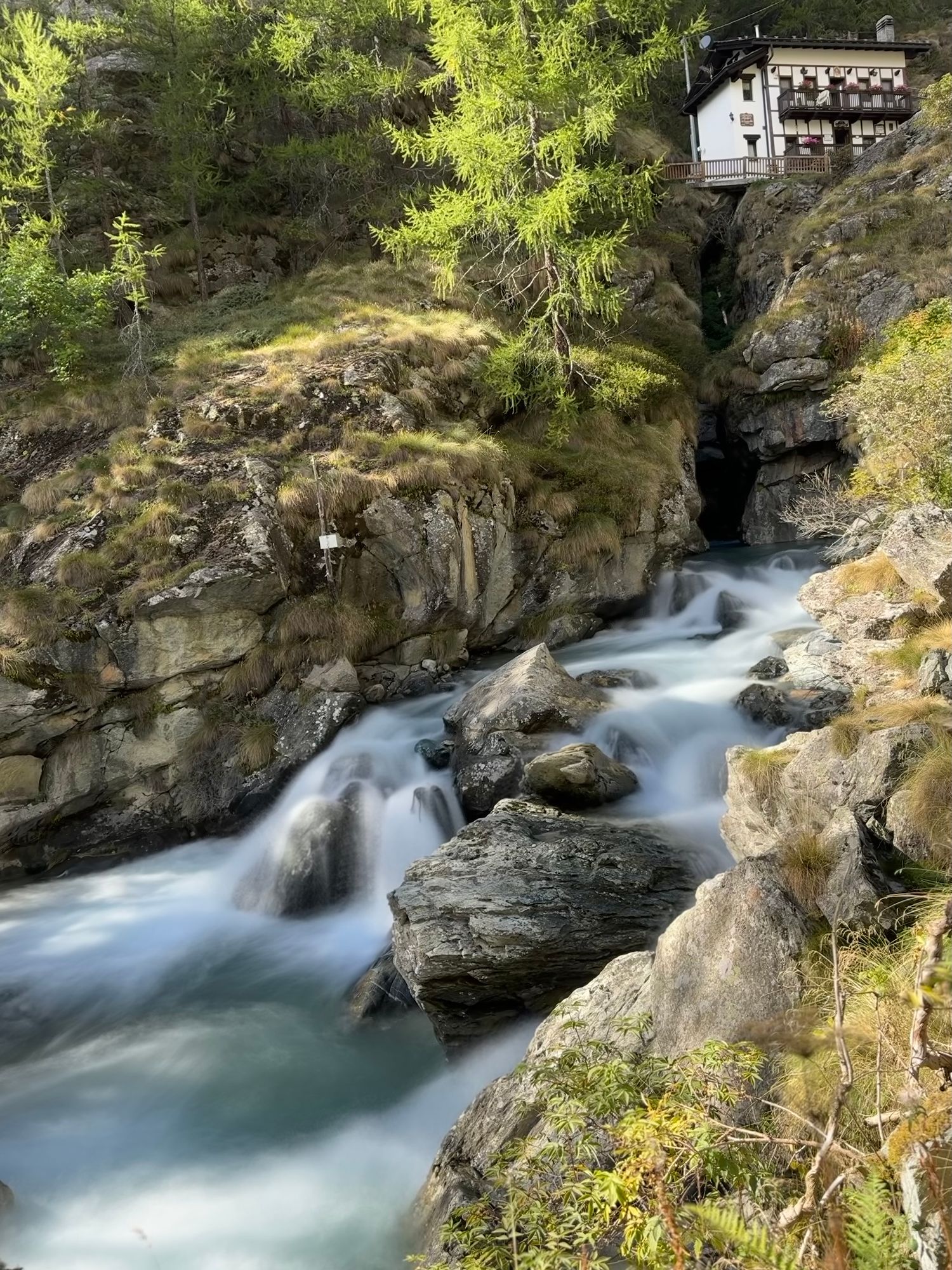 Daytime picture of a river running in the middle of the woods. The river is full of rocks and the water has a smooth appearance caused by the long exposure shot