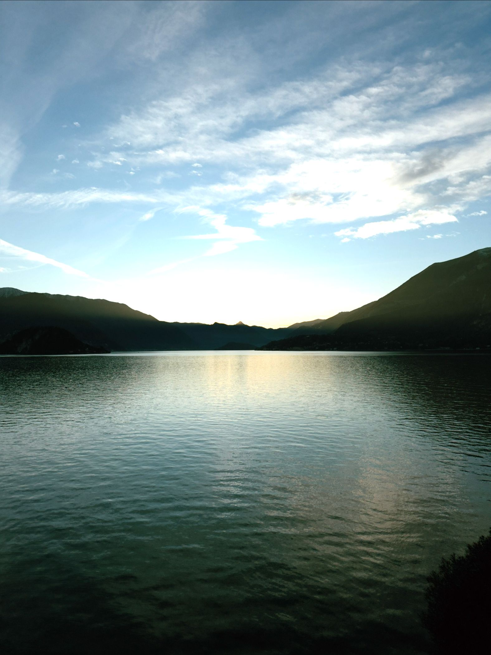 Shot of the blue lake waters slightly lit up by the last rays of sunlight of the day.