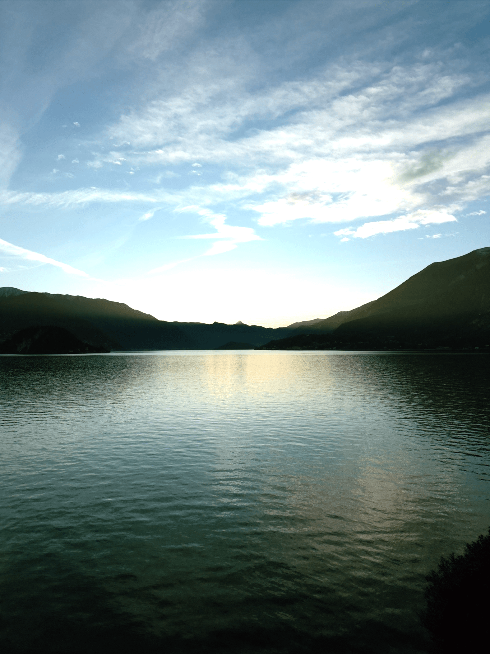 Shot of the blue lake waters slightly lit up by the last rays of sunlight of the day.